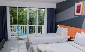 a bedroom with two beds , one on each side of the room , and a window overlooking a swimming pool at Grand Elty Krakatoa