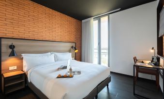 a large bed with white linens is situated in a room with brick walls and a window at Onomo Hotel Casablanca Airport