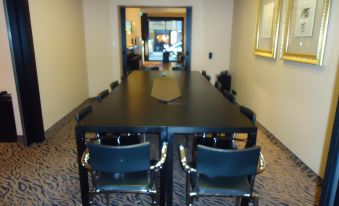 a long dining table with black chairs is set up in a room with an exit sign at Hotel Concorde