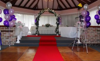 a large room with a red carpet and an archway decorated with flowers , chairs , and balloons at Abcot Inn
