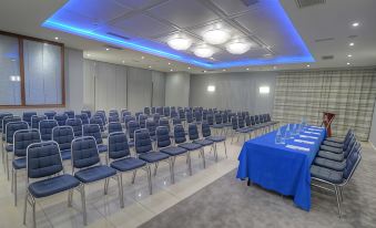 a conference room with rows of blue chairs and a blue tablecloth on the table at Alexandra Hotel