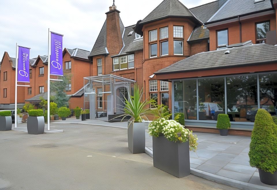 a brick building with a blue banner and flowers in front of it , possibly a hotel or an office building at Glynhill Hotel & Spa Near Glasgow Airport