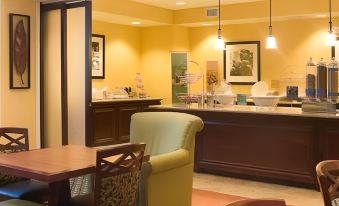 a dining area with a table and chairs , as well as a kitchen counter with various appliances and utensils at Hampton Inn & Suites Lake Wales