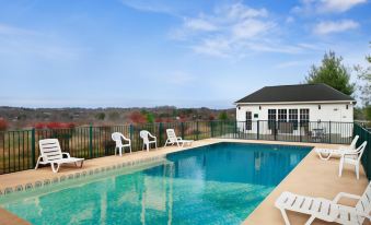 a large swimming pool with white lounge chairs and a white building in the background at Comfort Inn