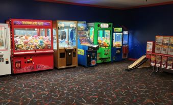 a room filled with various arcade games , including claw cranes , pinball machines , and video games at AmericInn by Wyndham Mounds View Minneapolis