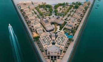 aerial view of a large , modern apartment complex with multiple buildings and a body of water in the background at Atana Musandam Resort