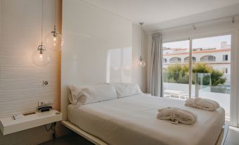 a white bedroom with a king - sized bed and a large window overlooking a body of water at Lago Resort Menorca Casas del Lago