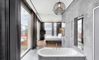 a modern bedroom with a large window and sliding glass door , featuring a bathtub in the bathroom at HYPERION Hotel Leipzig