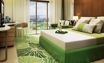 a hotel room with a green and white color scheme , featuring a king - sized bed and a view of the ocean at Timberland Highlands Resort