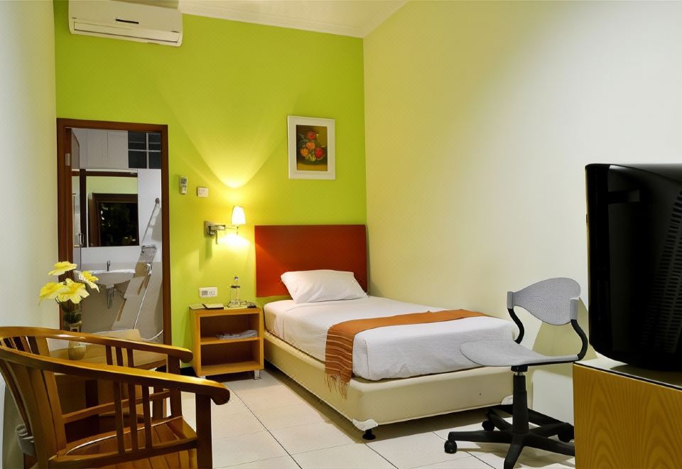 a modern hotel room with green walls , white beds , and furniture , including a desk , chair , and nightstand at Hotel Kings Kudus