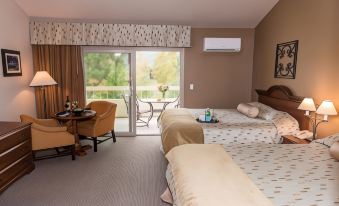 a hotel room with two beds , a dining table , and an open door leading to a balcony at San Vicente Golf Resort