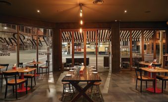 a modern restaurant with wooden tables and chairs , large windows , and an open bar area at Vibe Hotel Sydney