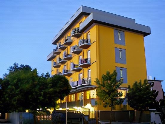 a large , modern apartment building with balconies and a blue sky in the background , illuminated by lights at Hotel Viking