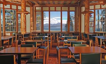 a large , well - lit room with wooden tables and chairs arranged in rows , providing a comfortable environment for people to sit and enjoy the view at Lake Lodge