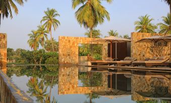 a serene scene with a pool surrounded by palm trees , and a wooden deck with umbrellas at Karpaha Sands