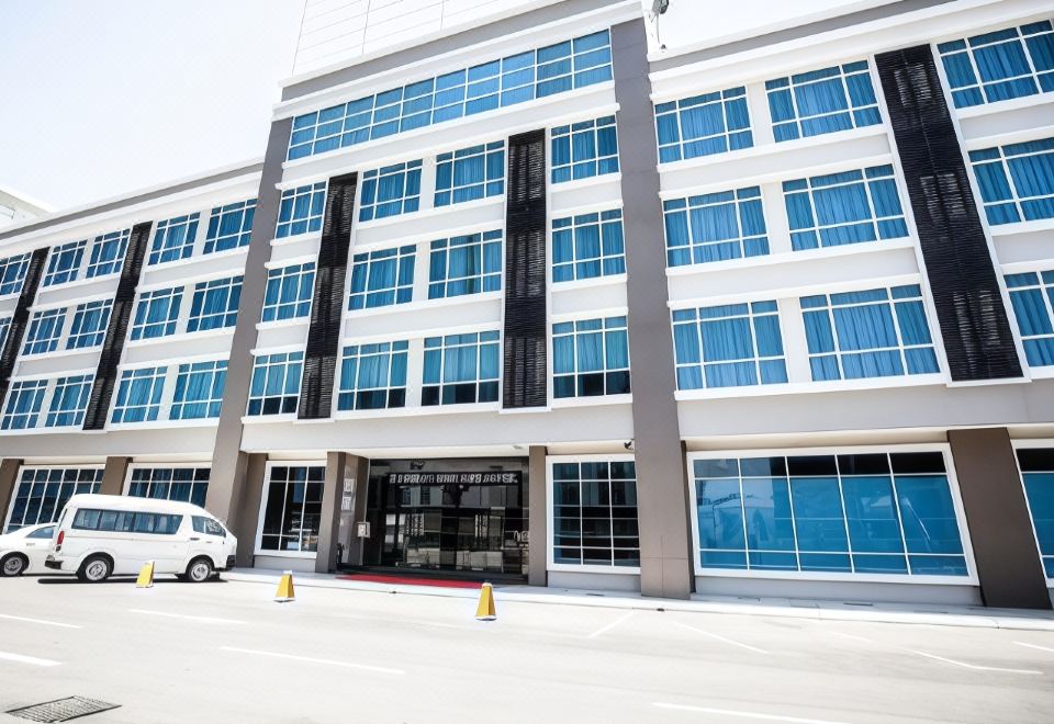 a modern building with blue and white exterior , large windows , and a red door , standing in front of a parking lot at Putatan Platinum Hotel