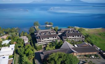 aerial view of a large resort with multiple buildings and a body of water in the background at Te Moana Tahiti Resort