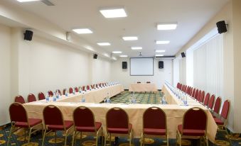 a conference room set up for a meeting , with chairs arranged in rows and a projector on the wall at Petro Sport Hotel