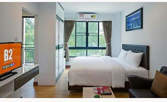 a hotel room with a large bed , a tv , and a window overlooking a cityscape at B2 Sriracha Premier Hotel