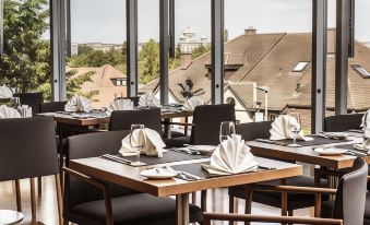 a restaurant with several dining tables set up for guests to enjoy a meal and enjoy the view at Hotel Ambassador