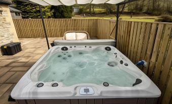 a hot tub is filled with water and bubbles , surrounded by a wooden fence and a chair at Lovelady Shield Country House Hotel