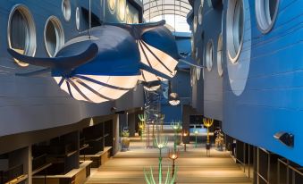 a modern building with large windows , a blue ceiling , and several blue fish - shaped decorations hanging from the ceiling at Beyond Patong