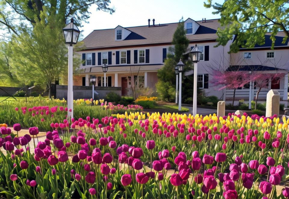 a colorful flower garden in front of a house , with a variety of flowers blooming at The Inn at Montchanin Village