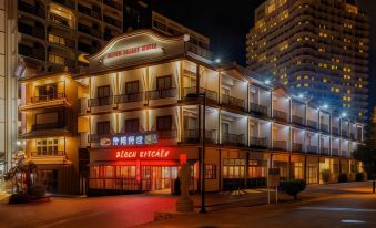 a large building with a restaurant sign on the front , illuminated at night against the backdrop of a busy street at Sunset Beach Hotel