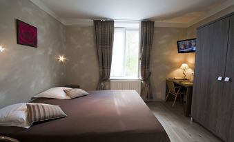 a bedroom with a bed , two lamps , and a window with curtains , as well as a desk and chair at Logis la Résidence