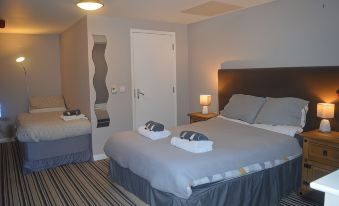 a modern hotel room with two beds , each made up with gray linens and white towels at The Queen Victoria