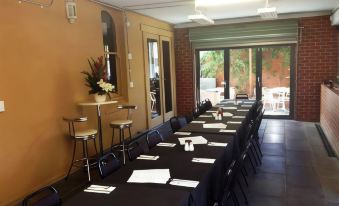 a large conference room with black tables and chairs , set up for a meeting or event at Seymours on Lydiard