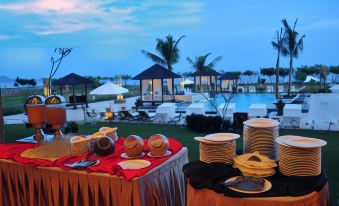 a table with a red cloth and plates of food is set up in front of a pool at The Jayakarta Suites Komodo Flores