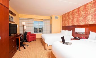 a hotel room with two beds , a laptop on one bed , and a red couch at Courtyard Peoria Downtown