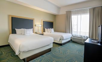 a hotel room with two beds , one on the left and one on the right side of the room at SpringHill Suites Pueblo Downtown