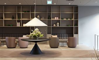 a modern living room with a black table surrounded by pink chairs and a large white vase at Hotel Odeon