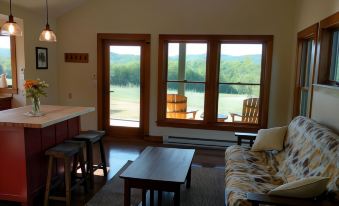 a living room with a couch , dining table , chairs , and a view of a lake at Fat Sheep Farm & Cabins