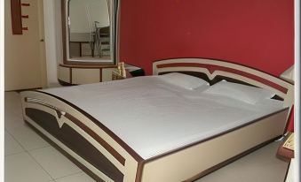 a large bed with white sheets and a brown headboard is in a room with red walls at Pinky Hotel