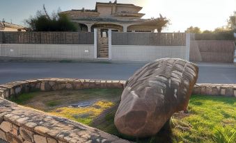 a large rock in a garden , surrounded by a stone wall , and situated near a house at Il Tramonto