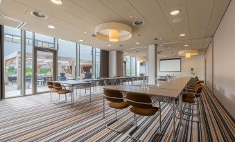 a large conference room with rows of chairs arranged in a semicircle , and a projector mounted on the wall at Leonardo Hotel Papendrecht