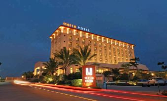 a large hotel building surrounded by palm trees , with the hotel 's name displayed prominently above the entrance at Brittany Hotel Global South Formerly Mella Hotel