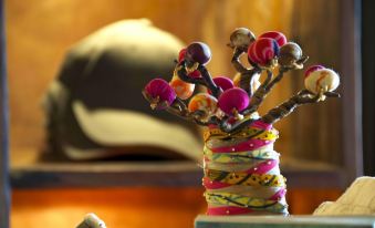 a vase filled with colorful ornaments is placed on a table next to a hat at Elewana Tarangire Treetops