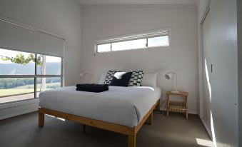 a large bed with a wooden headboard and footboard is situated in a room with white walls , a window , and a nightstand at Stay in Mudgee