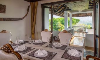 a dining room with a table set for a meal , complete with plates , cups , and utensils at Gassan Khuntan Golf & Resort