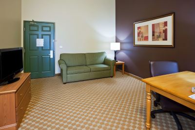 a hotel room with a green couch , a wooden table , and a framed picture on the wall at Country Inn & Suites by Radisson, Watertown, SD
