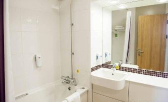 a white bathroom with a sink , bathtub , and mirror , as well as towels on the counter at Premier Inn Liverpool (Tarbock)