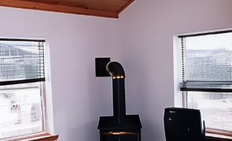 a cozy living room with a fireplace , wooden ceiling , and large windows that offer views of the city at Chisholms of Troy Coastal Cottages