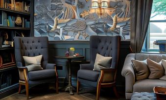 a room with a large mural on the wall , two chairs , and a small table at Beadnell Towers Hotel