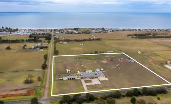 aerial view of a large building complex with a green field in front of it , near the ocean at The Oxley Estate