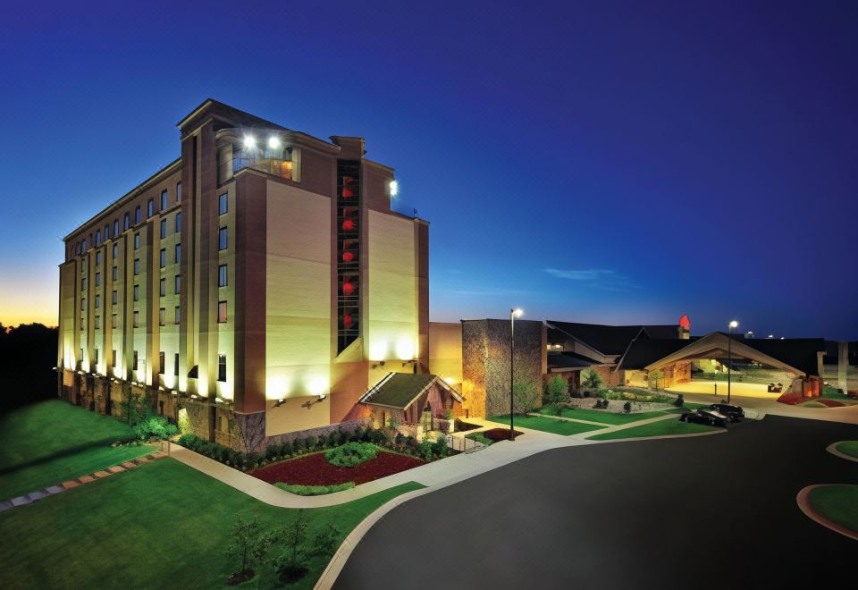 a large hotel with a red sign and two parking lots in front of it at Cherokee Casino West Siloam Springs Resort