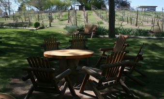 a group of wooden chairs and a table are set up in a garden area at Dreamcatcher Bed and Breakfast